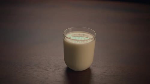 Hand Takes Glass of Milk on Table