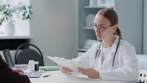 Female Doctor Examining Medical Document and Consulting Patient at Clinic