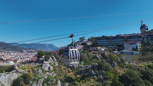 Aerial Video Cable Car Lifting People Over the Mountains With Vibrant Sea and Urban Views Below