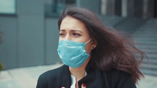 Woman Wearing Face Mask Holds Chest in City