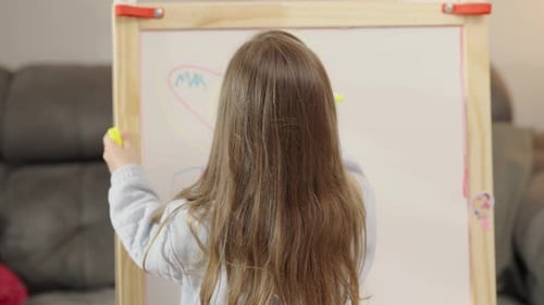 Child Drawing on Whiteboard Easel at Home