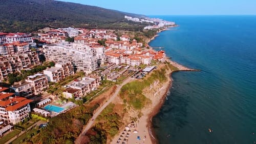 Seaside resort with yachts and red roof houses on the coast.