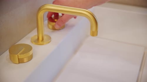 Der Mann öffnet den Wasserhahn von Hand, um Wasser zu sparen, indem er den Wasserhahn im Badezimmer aufdreht, Nahaufnahme