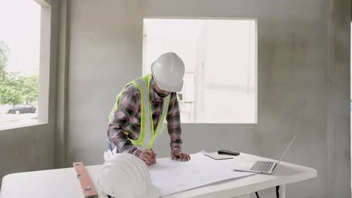 Man multiethnic wearing green reflective vests and safety helmets in house under construction. India