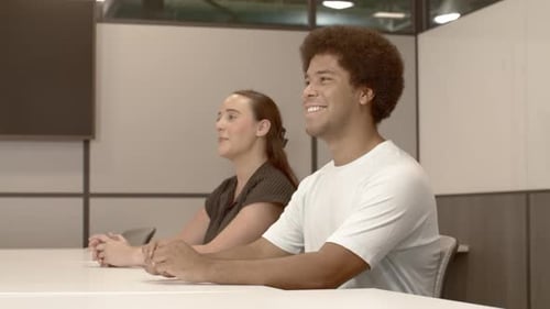 African American male in his 20's and a caucasian female in her 20's talking in business meeting wit