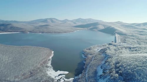 Aerial View on a Blue Lake Between the Snowy Mountains and Iced Frozen Forest Beautiful Winter