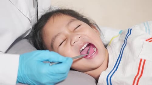 Dentist Checking Child Patient Teeth with Dental Mirror