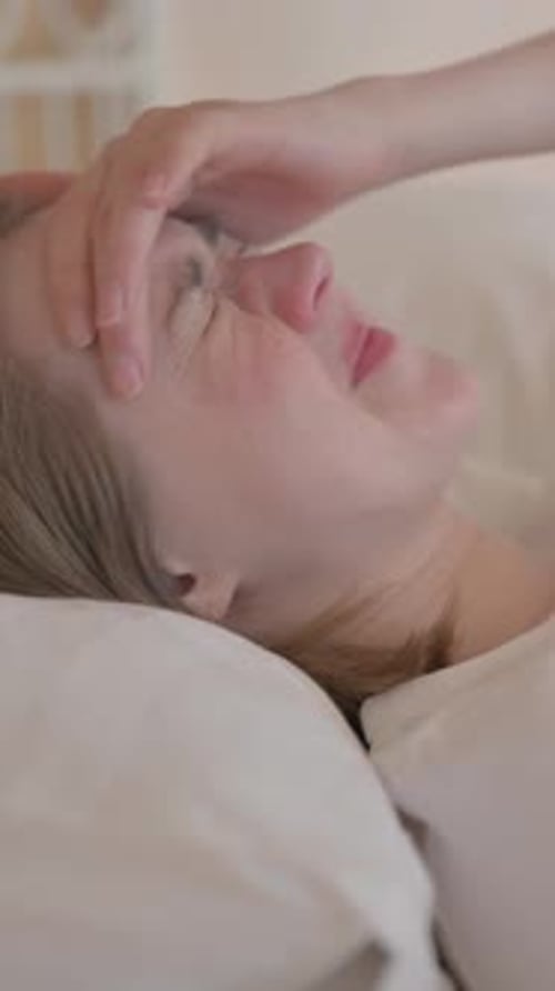 Side View of Young Woman with Headache Lying in Bed, vertical video