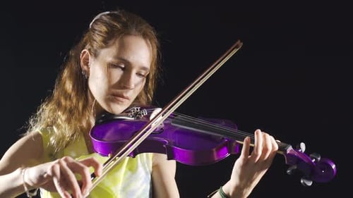 The female violinist plays the violin at the music school, the musician plays the violin at the oper