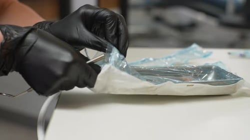 Abgeschnittene Nahaufnahme eines unkenntlichen Zahnarztes in Schutzhandschuhen, der desinfizierte Koffer öffnet mit