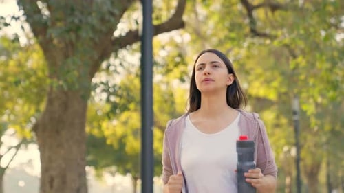 Woman Jogging in Park with Water Bottle