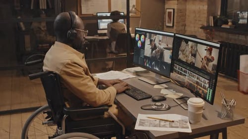 Man Sitting at Desk in Wheelchair Working in Office