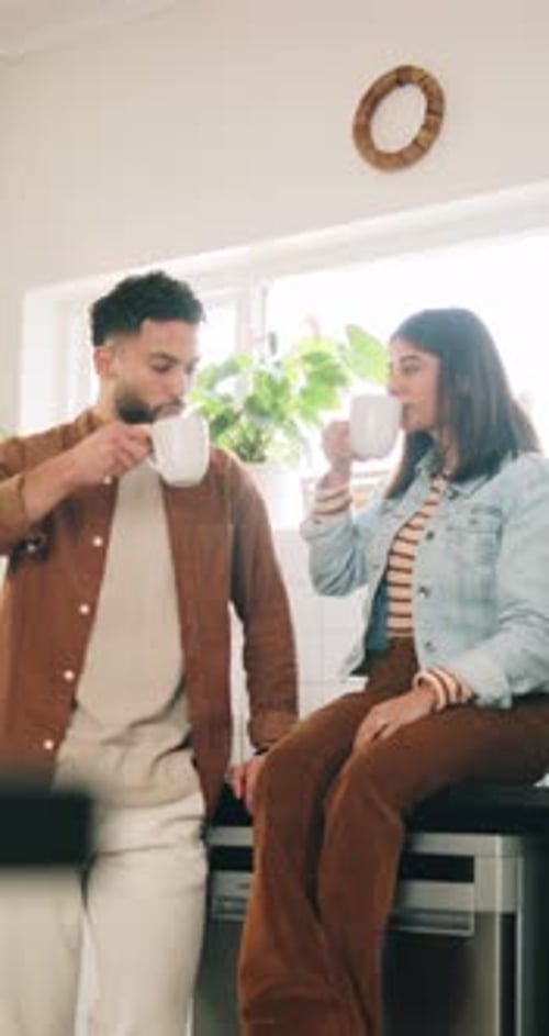Young Couple Chatting Over Drinks in Kitchen