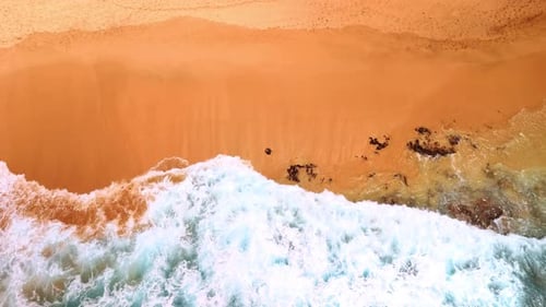 Waves arrive to the beautiful sandy beach. Drone footage above the shore of the ocean.