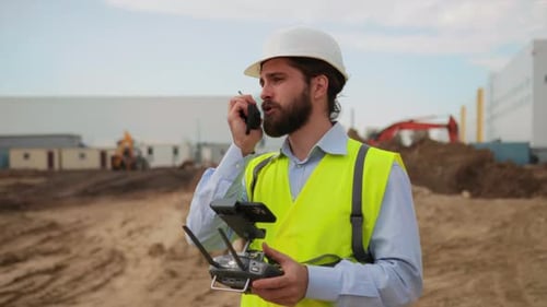 Portrait of Male Engineer Using Walkietalkie During Work at Construction Area Young Bearded