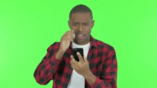 African Man with Loss on Phone on Green Background