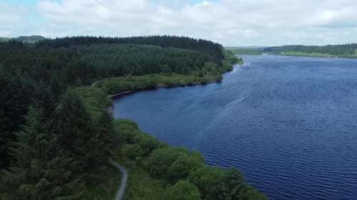Idyllic blue water reservoir lake woodland hiking walk aerial view descending to shoreline