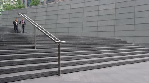 Businessman and Businesswoman walking out of office down stairs