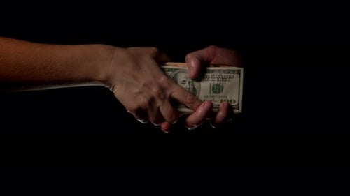 Hands transfer money on a black background after bank fraud