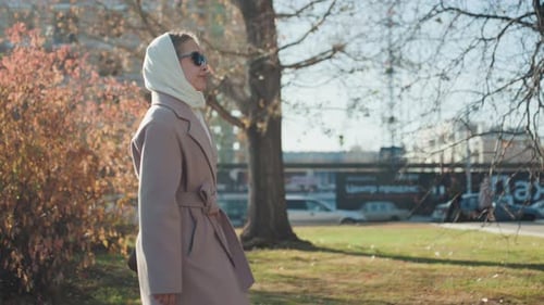 Stylish Woman Strolling Chic Lady in City Park with Soft Sunlight Glow Fashionable Woman Wearing