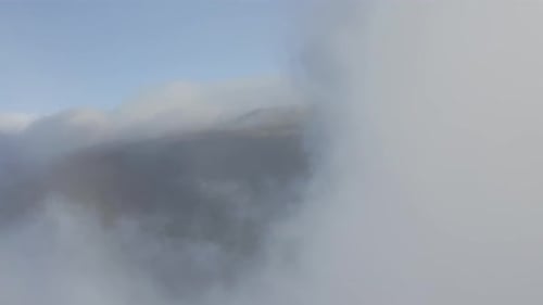 Fly through white clouds moving over the slopes of Haleakala volcano on Maui at daylight. Drone view