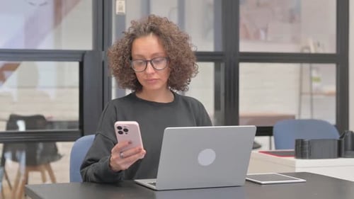 Woman with Phone and Laptop at Desk