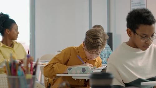 Diverse Students Writing in Bright Classroom Setting