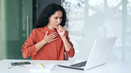 Woman Working at Laptop Coughs in Office