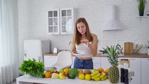 Young Woman Eats Berries in Bright Kitchen