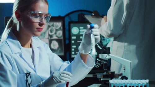 Scientists Experimenting with Microscope and Blood Samples