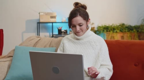 Woman Uses Laptop and Smiles on Couch