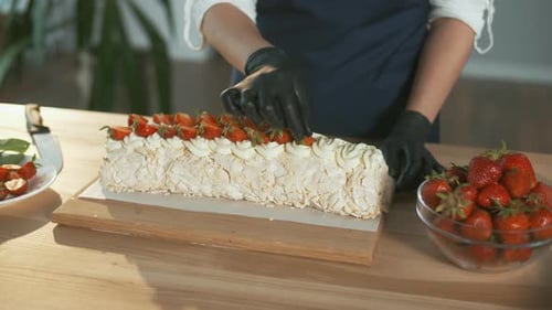 Primer plano: el pastelero pone fresas frescas en un pastel de merengue con crema