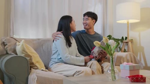 Woman Gives Flowers to Man on Couch