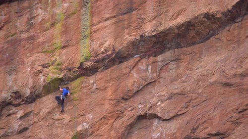 Woman climbing a steep rock using climbing gear