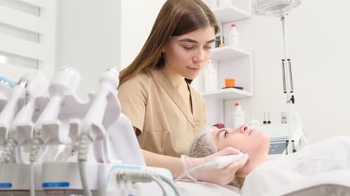 A Dermatologist Examines the Skin on a Young Woman's Face A Beautician at Work in His Office