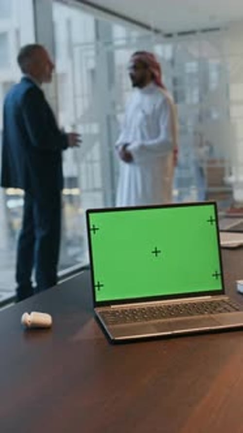 Laptop with Chroma Key Screen, Diverse Entrepreneurs Negotiating in Background