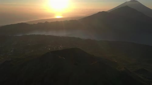 Light rays shining onto amazing tropical Bali Island with Mount Batur volcano, aerial