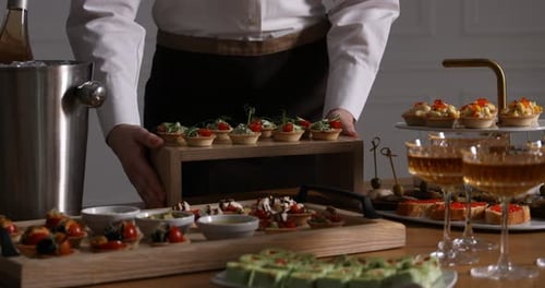 Waiter arranging appetizers for buffet at table, closeup