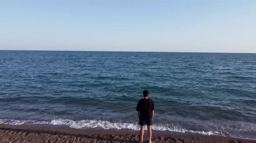 Young man watching the sea at the beach 4K