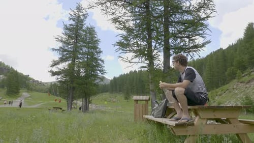 Young Adult Relaxing with Water on Picnic Bench