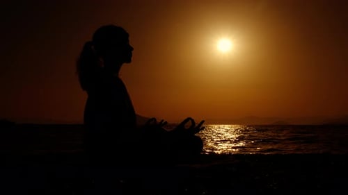Woman Silhouette Meditating at Beach During Sunrise