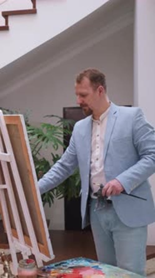 Man in Suit Painting on Canvas Indoors