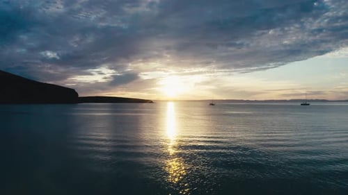Arial shot of an incredibly gorgeous sunset over the ocean. Silhouettes of lone sailing boats are th