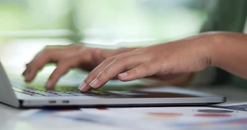 Hands Typing on Laptop Keyboard in Office