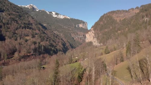 Wide aerial shot of a scenic valley with snow covered mountains in the background