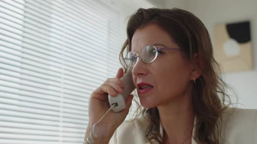 Woman On Landline Phone In Office Talking