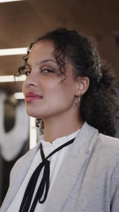 Vertical video of portrait of happy biracial businesswoman in casual office, slow motion