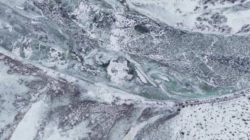 Aerial Perspective Of A Winding Frozen River Through Snowy Terrain