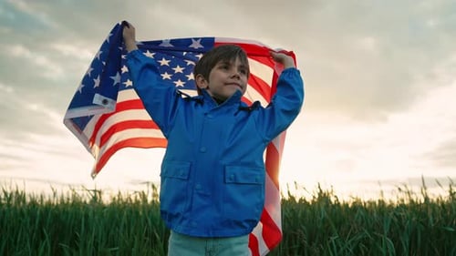 Young Boy Holding American Flag in Field at Sunset