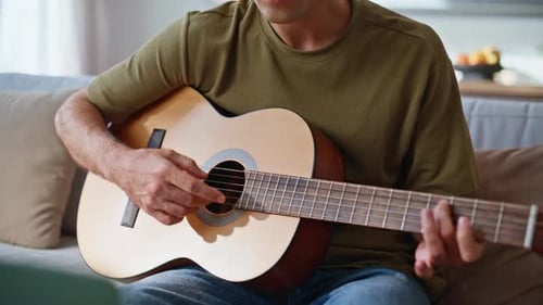 Manos de guitarrista ensayando la canción en casa, de cerca, hombre relajado disfrutando de la música